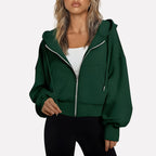 Woman wearing a dark green cropped zip hoodie in a studio setting