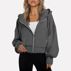 Woman wearing a dark grey cropped zip hoodie in a studio setting