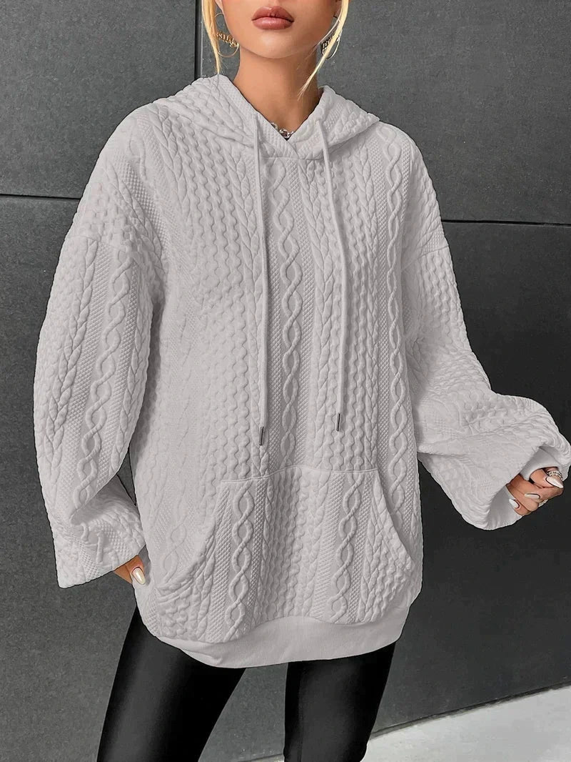 Woman wearing grey oversized cable-knit hoodie with drawstring