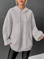 Woman wearing grey oversized cable-knit hoodie with drawstring