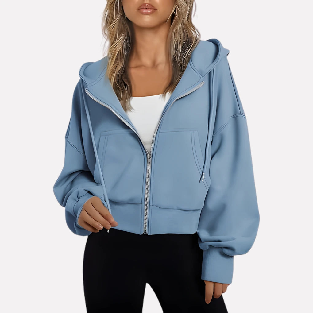 Woman wearing a light blue cropped zip hoodie in a studio setting