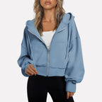 Woman wearing a light blue cropped zip hoodie in a studio setting