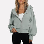Woman wearing a light grey cropped zip hoodie in a studio setting