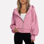 Woman wearing a light pink cropped zip hoodie in a studio setting