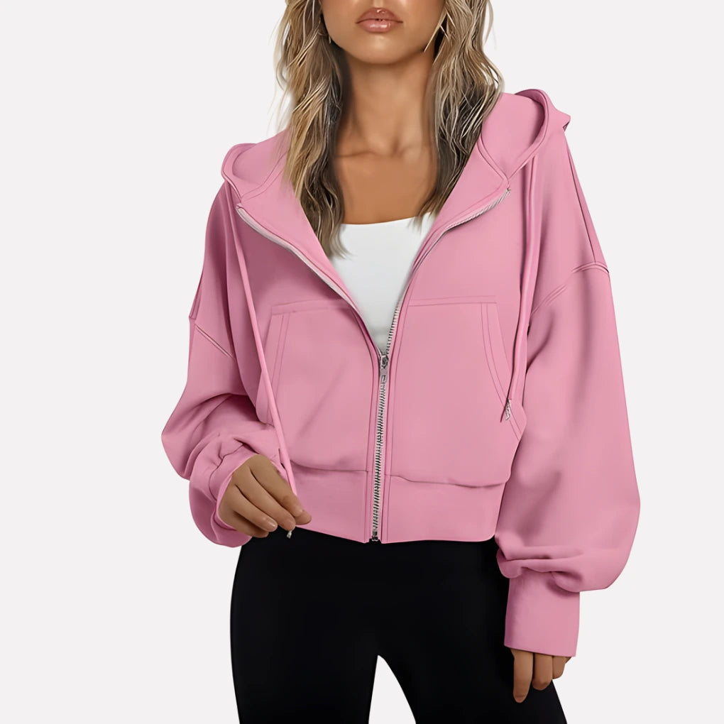 Woman wearing a light pink cropped zip hoodie in a studio setting