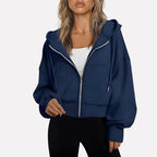 Woman wearing a navy blue cropped zip hoodie in a studio setting