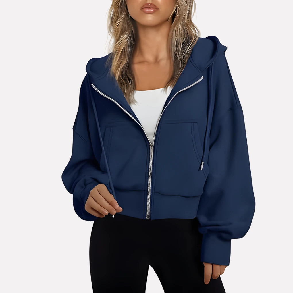 Woman wearing a navy blue cropped zip hoodie in a studio setting