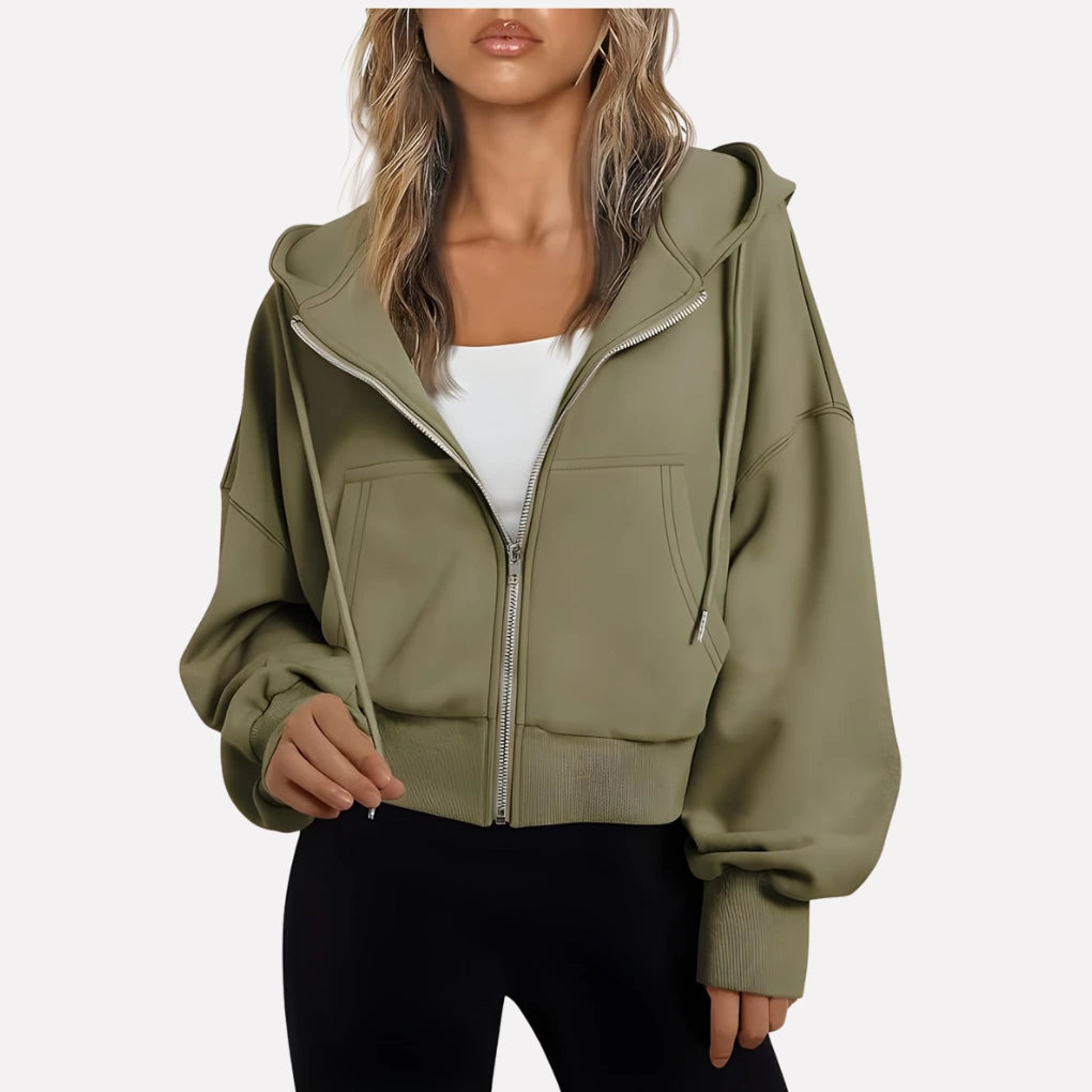 Woman wearing an olive green cropped zip hoodie in a studio setting