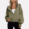 Woman wearing an olive green cropped zip hoodie in a studio setting