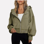 Woman wearing an olive green cropped zip hoodie in a studio setting