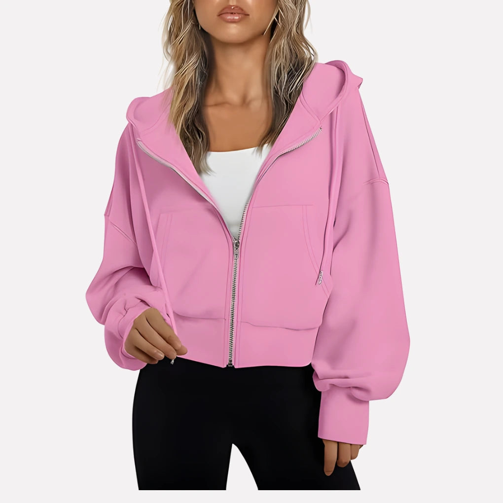 Woman wearing a pink cropped zip hoodie in a studio setting