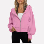 Woman wearing a pink cropped zip hoodie in a studio setting