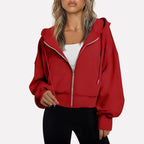Woman wearing a red cropped zip hoodie in a studio setting