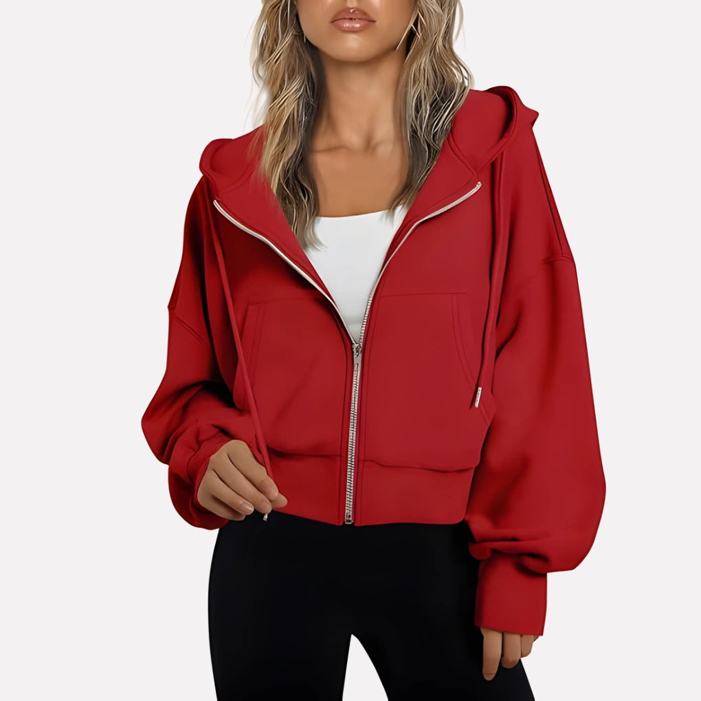 Woman wearing a red cropped zip hoodie in a studio setting