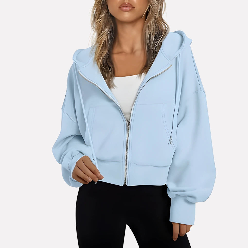 Woman wearing a sky blue cropped zip hoodie in a studio setting