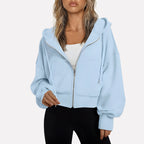 Woman wearing a sky blue cropped zip hoodie in a studio setting