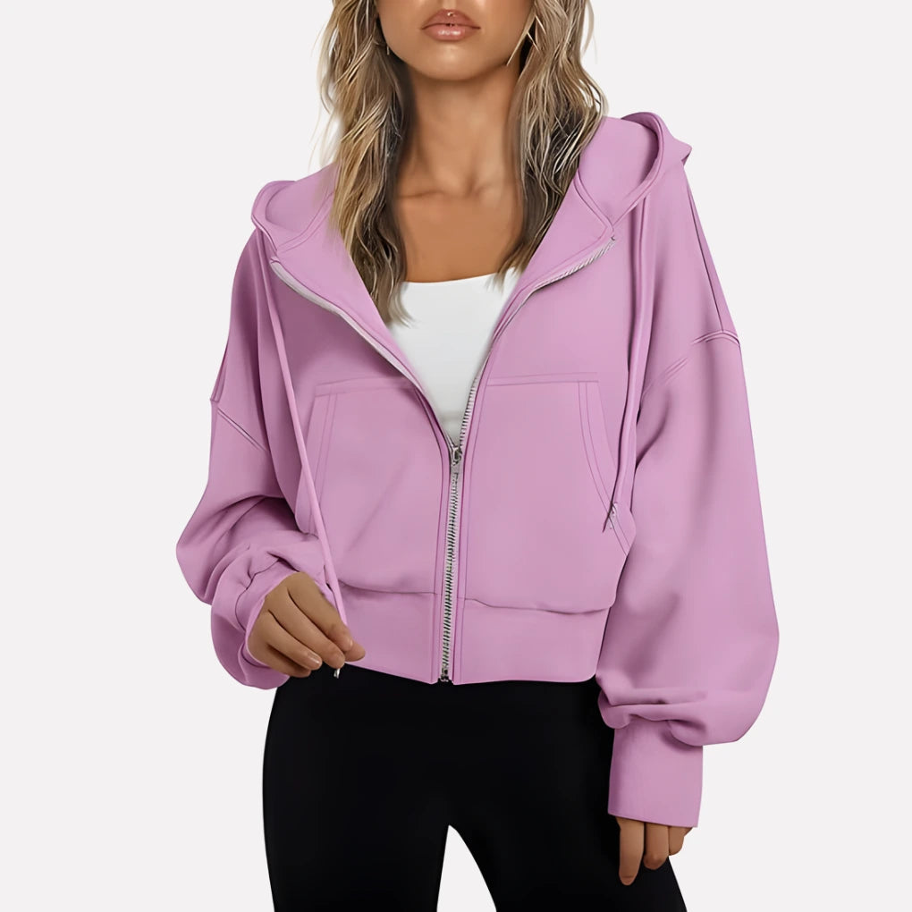 Woman wearing a soft pink cropped zip hoodie in a studio setting