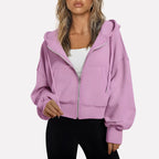 Woman wearing a soft pink cropped zip hoodie in a studio setting
