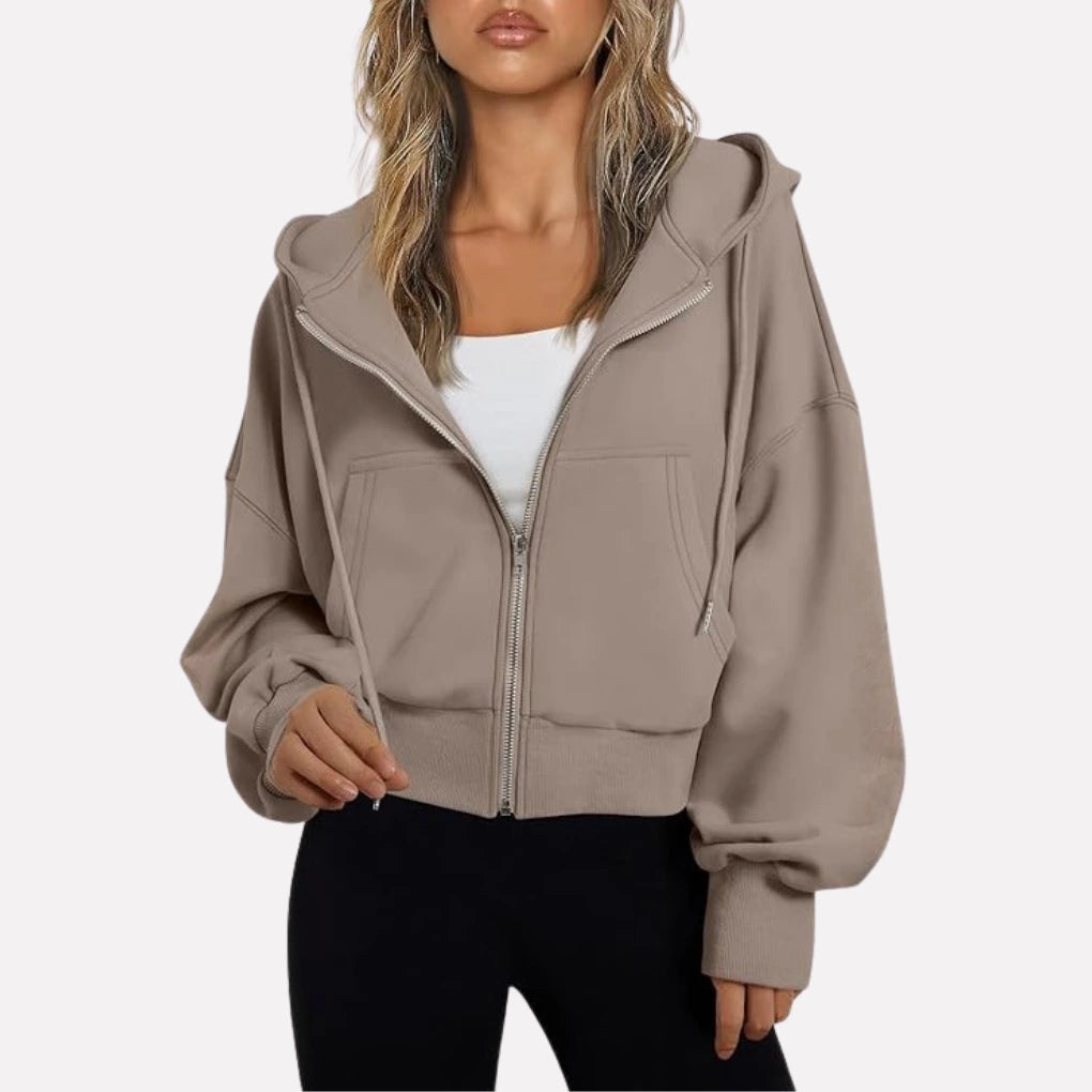 Woman wearing a taupe cropped zip hoodie in a studio setting