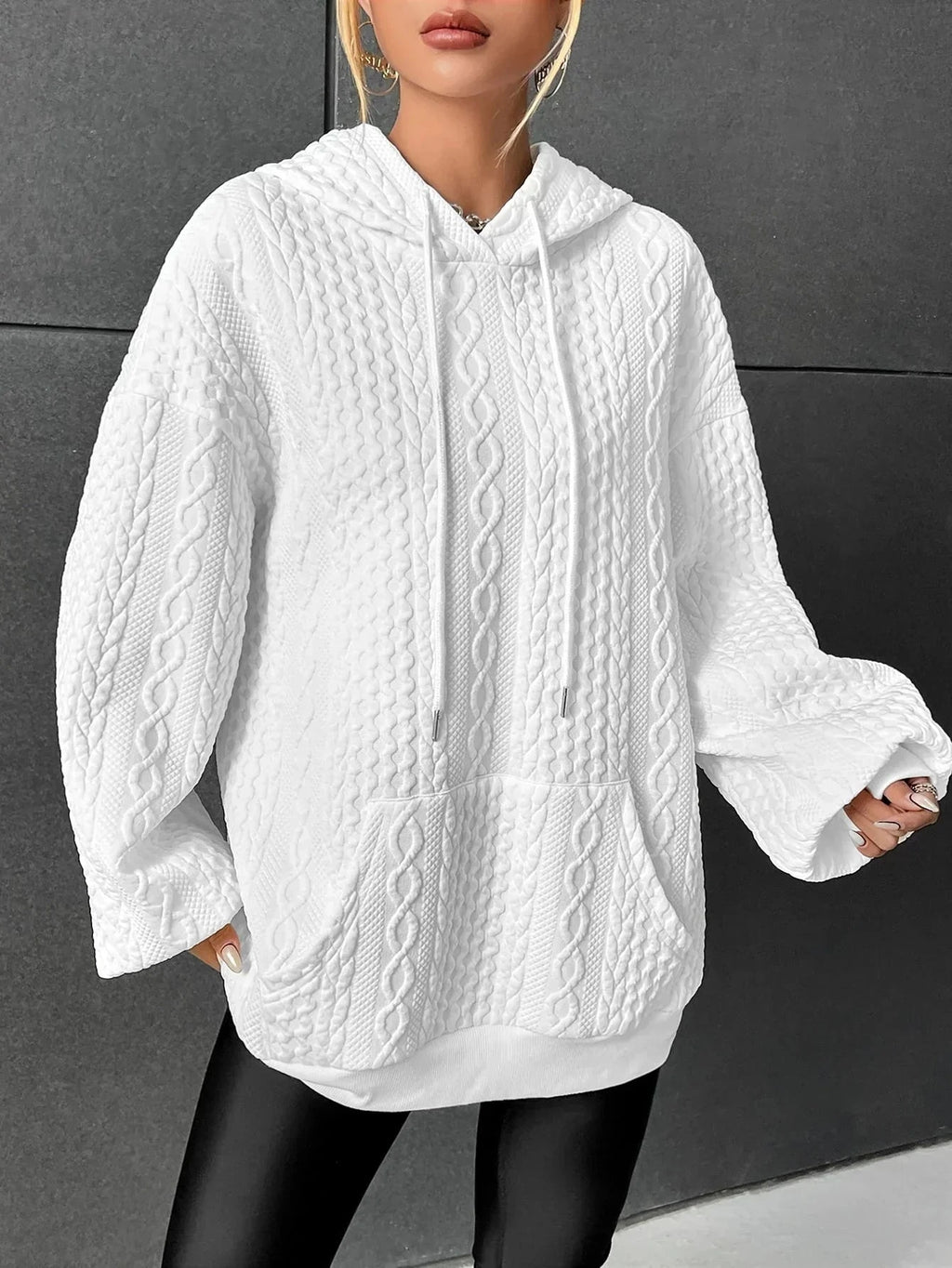 Woman wearing white oversized cable-knit hoodie with drawstring, front view