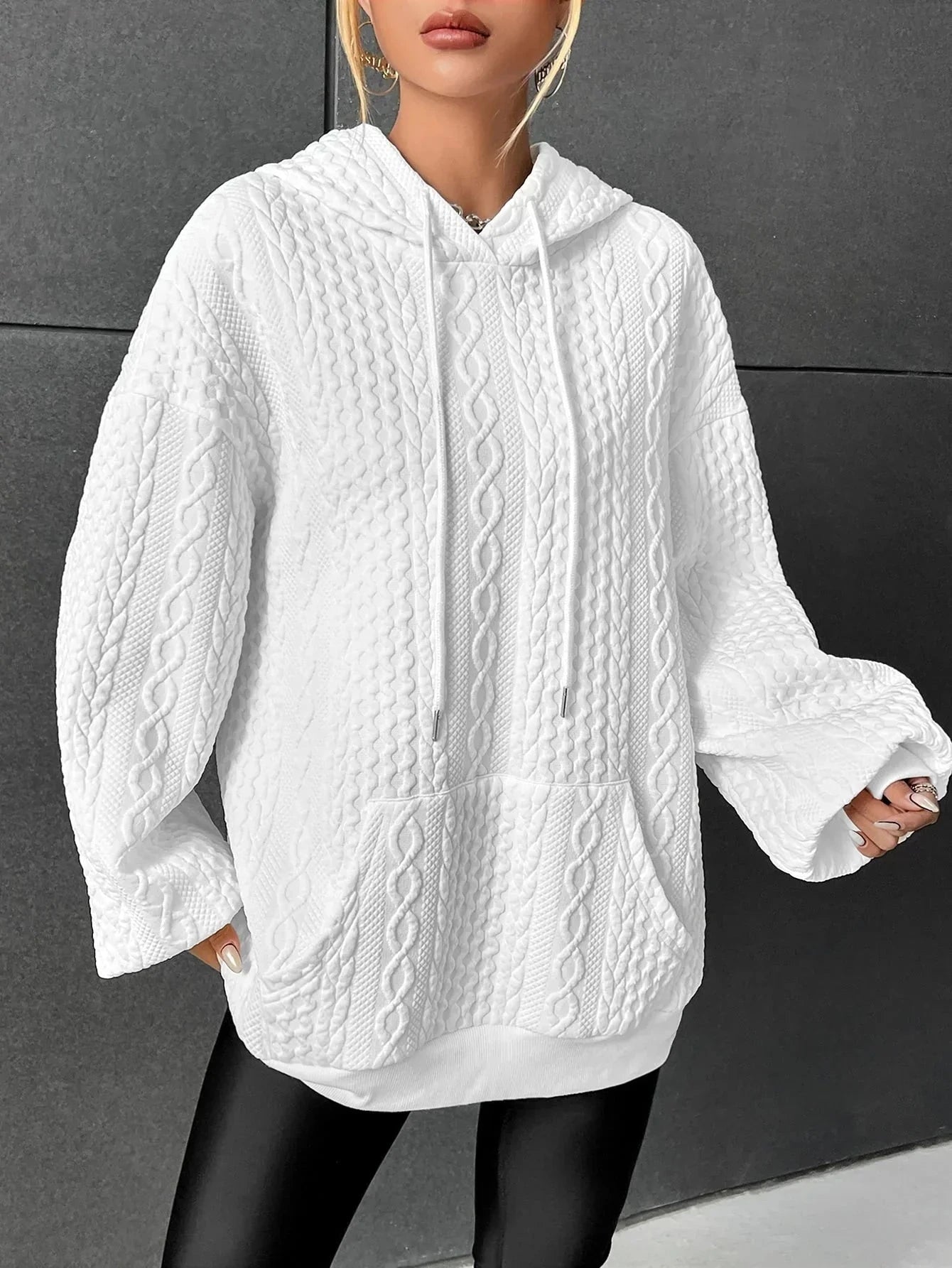 Woman wearing white oversized cable-knit hoodie with drawstring, front view