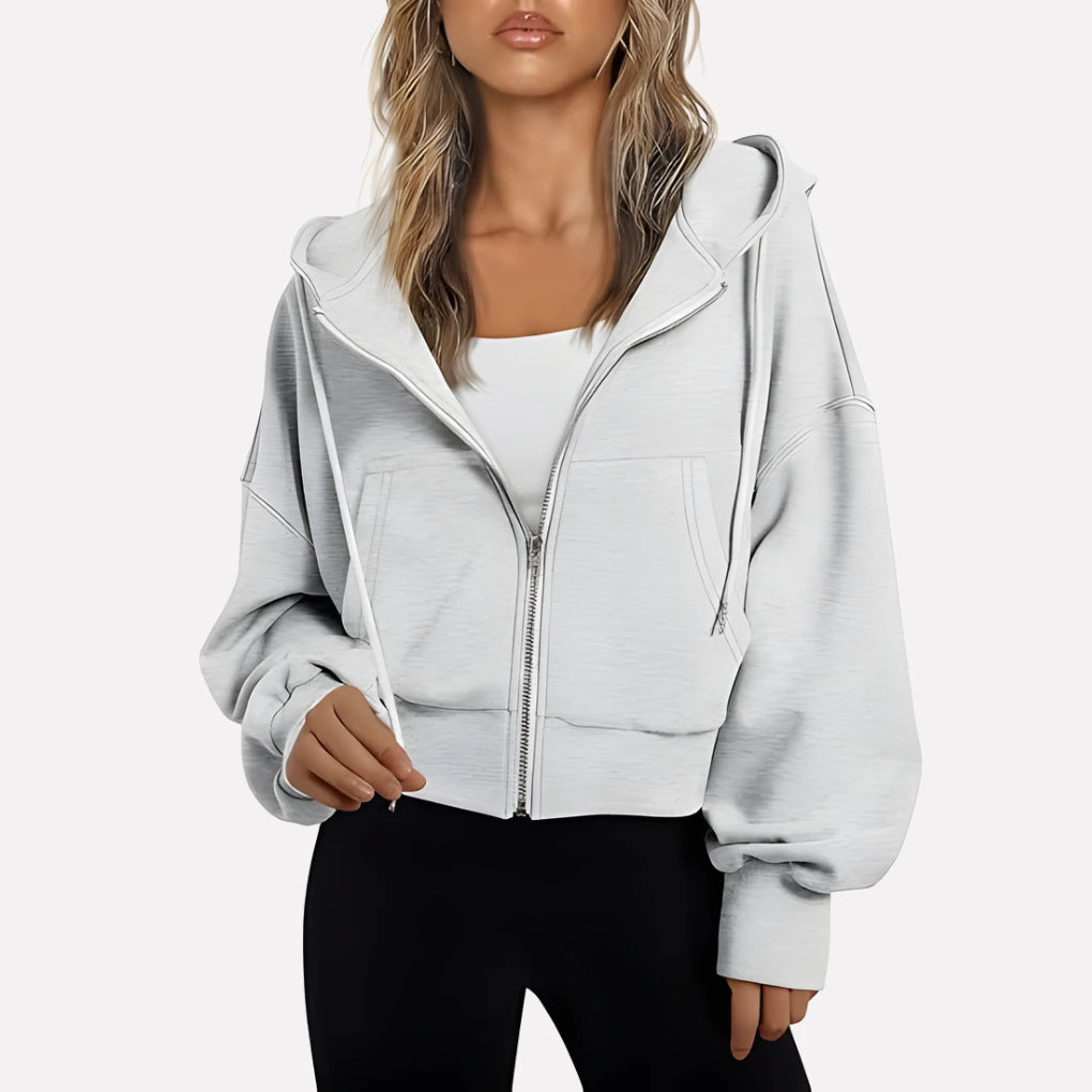 Woman wearing a white cropped zip hoodie in a studio setting