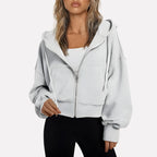 Woman wearing a white cropped zip hoodie in a studio setting