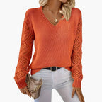 Woman wearing orange knitted V-neck jumper with open sleeve detail