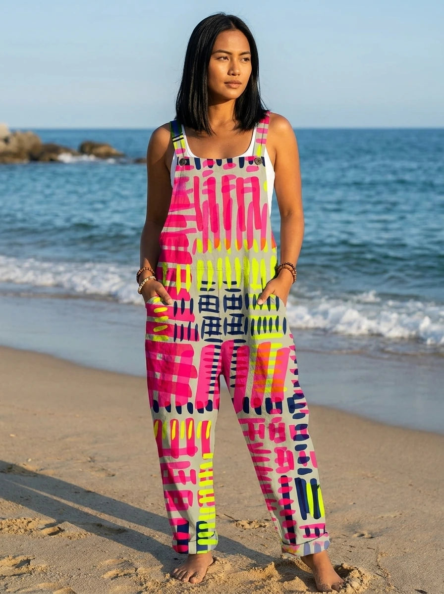 Woman wearing a jumpsuit with a pink, magenta and black abstract geometric print on the beach