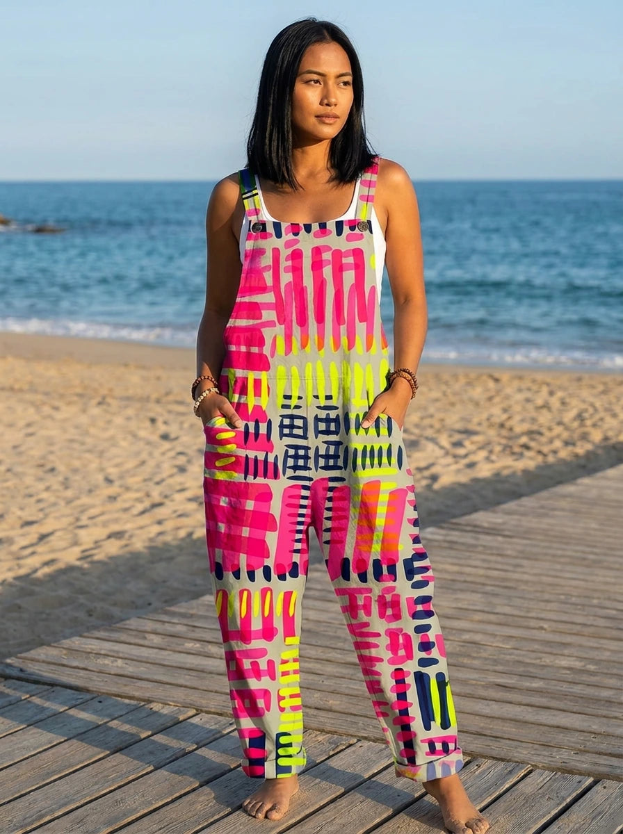 Woman in an abstract geometric print jumpsuit standing on a wooden beach boardwalk