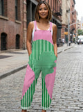 Woman wearing a pink and green abstract striped wide-leg overall jumpsuit standing on an urban street