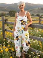 Woman in a white bee and blossom print jumpsuit leaning against a wooden fence