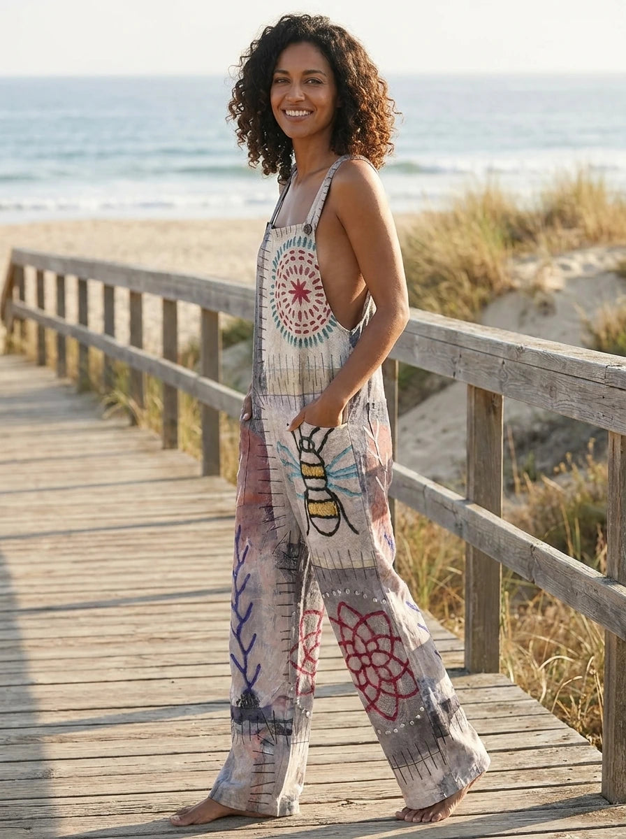 Woman standing on a wooden boardwalk wearing a bee print wide-leg jumpsuit