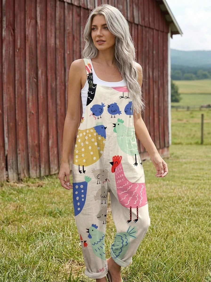Woman wearing a cream colorful bird print sleeveless wide-leg overall jumpsuit standing near a red barn