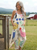 Woman wearing a cream colorful bird print sleeveless wide-leg overall jumpsuit standing in a farm field