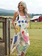 Woman wearing a cream colorful bird print sleeveless wide-leg overall jumpsuit standing in a farm field