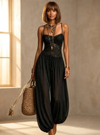 Woman wearing a black boho lace cami jogger jumpsuit in a studio setting