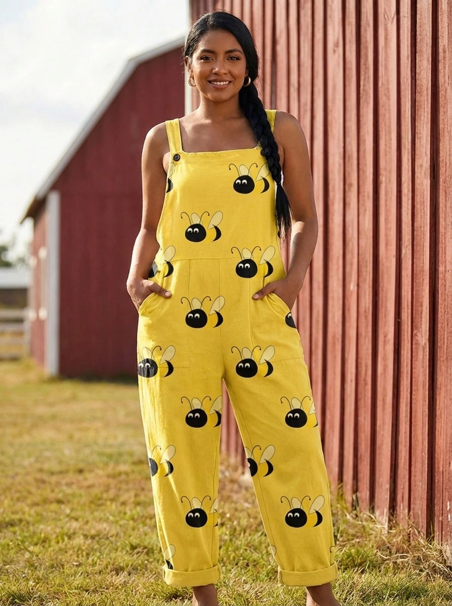 Woman in a yellow bumblebee print jumpsuit standing near a red barn