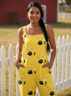 Woman in a yellow bumblebee print jumpsuit standing by a white picket fence