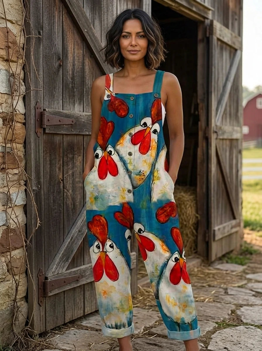 Woman wearing a teal chicken print sleeveless button-front overall jumpsuit standing near a wooden barn door