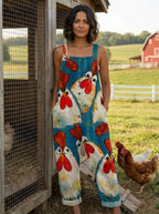 Woman wearing a teal chicken print sleeveless button-front overall jumpsuit leaning against a chicken coop fence