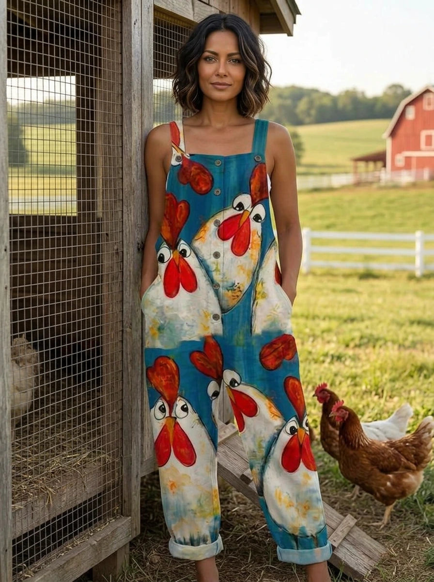 Woman wearing a teal chicken print sleeveless button-front overall jumpsuit leaning against a chicken coop fence