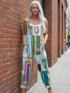 Woman wearing a grey multicolor geometric color-block wide-leg overall jumpsuit leaning against a brick wall