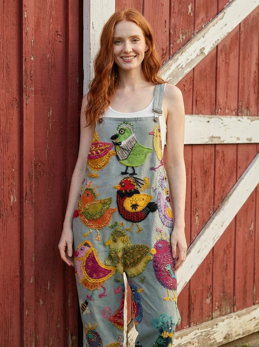 Woman in a colorful bird print jumpsuit standing by a red barn door
