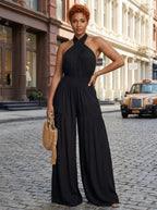 Woman wearing a black cross halter wide-leg jumpsuit on a city street