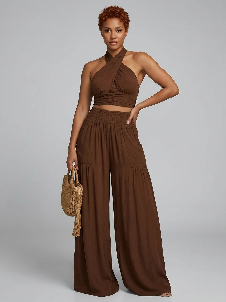 Woman wearing a dark brown cross halter wide-leg jumpsuit in a studio setting