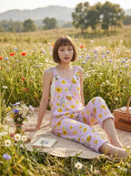 Woman in a lavender daisy and bee print jumpsuit sitting on a picnic blanket in a meadow
