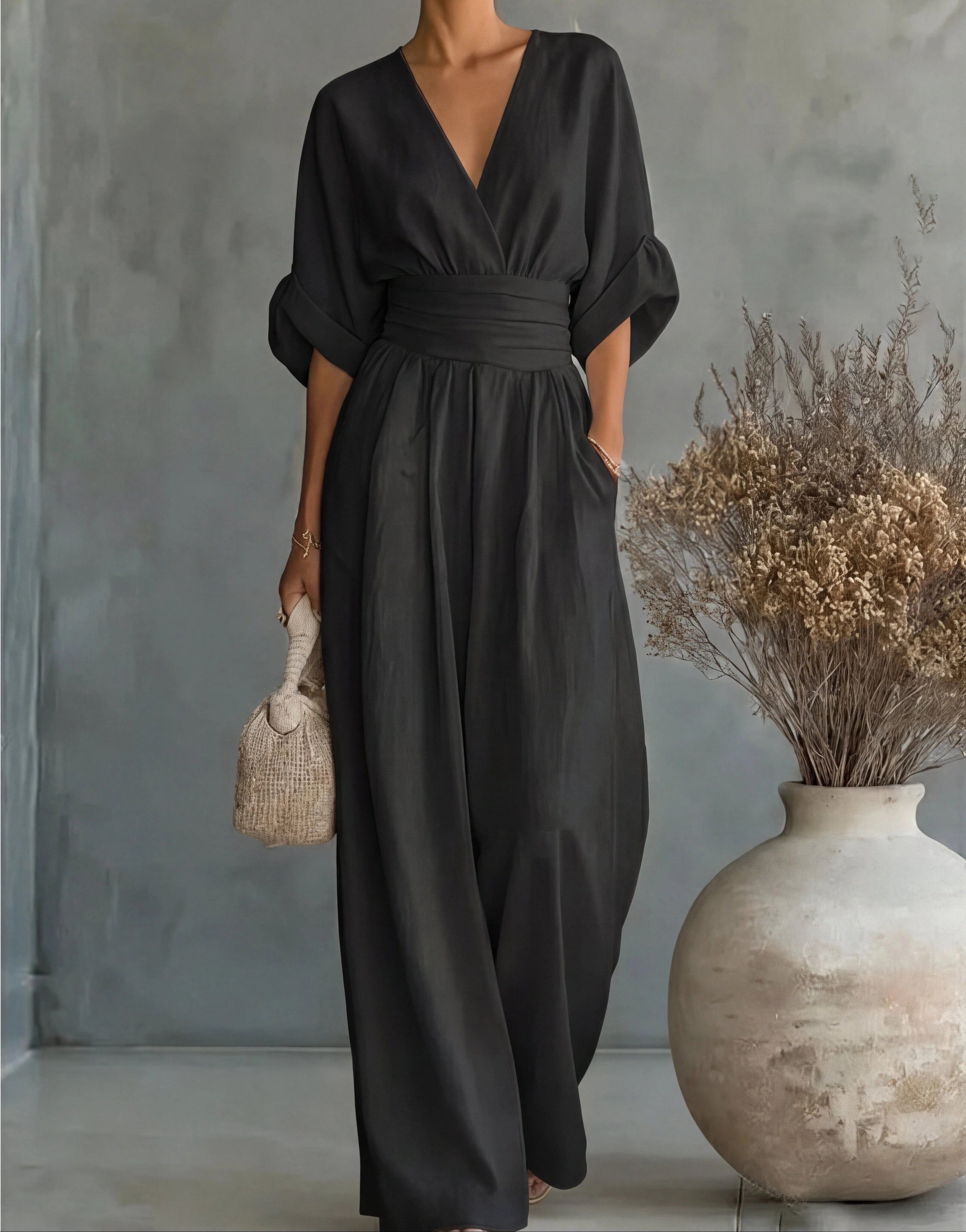 Woman wearing a black elegant wide-leg jumpsuit - studio photo