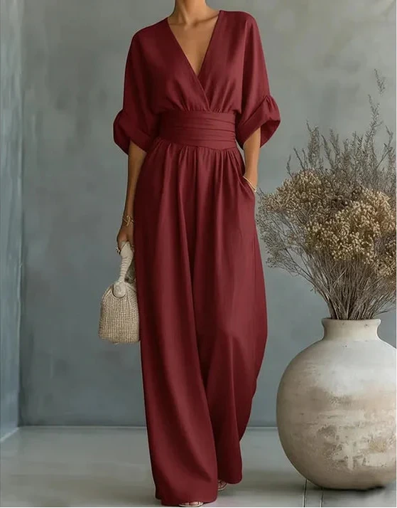 Woman wearing a burgundy elegant wide-leg jumpsuit - studio photo