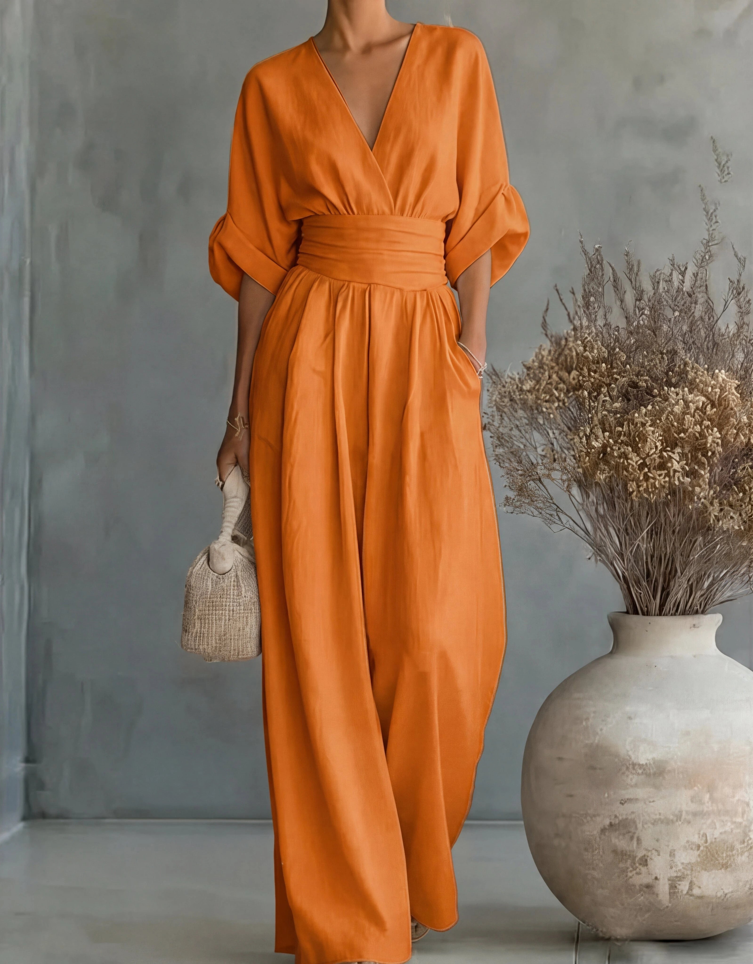 Woman wearing a orange elegant wide-leg jumpsuit - studio photo